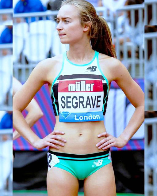 Female track athlete in green and white sportswear standing with hands on hips at a competition