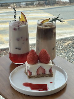 Iced orange latte, Korean strawberry milk, and a strawberry shortcake slice on a white plate at a café