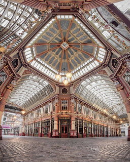Ornate Victorian covered market with decorated vaulted ceiling, glass roof, and cobblestone floor
