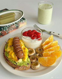 Plate with toast, sausage, eggs, yogurt, strawberries, orange slices, kiwi, and a glass of milk