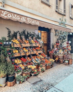 Colorful fruit and vegetable stand with wooden crates outside an Italian shop called L'orto di Brera