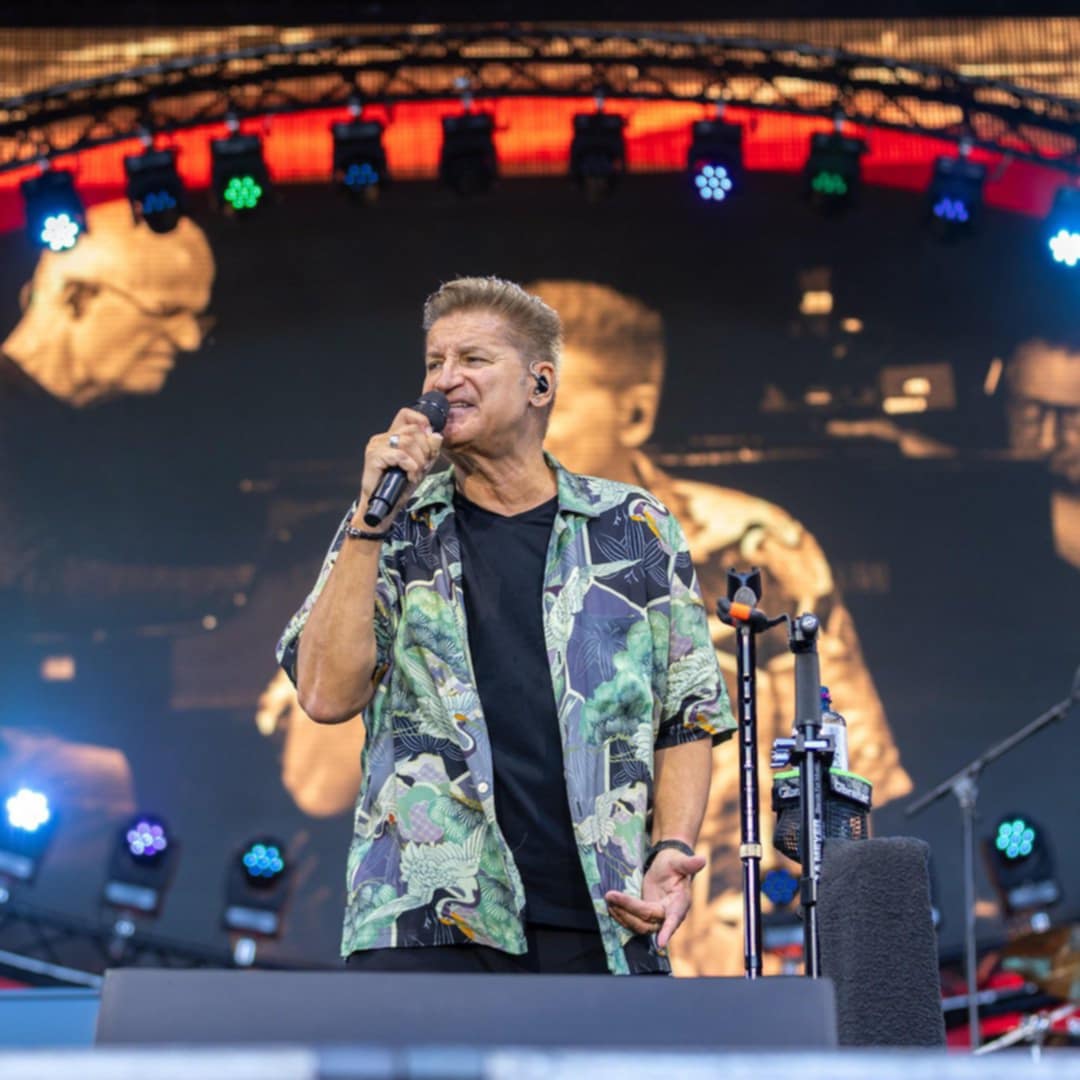 Male singer performing on stage with microphone and concert lights