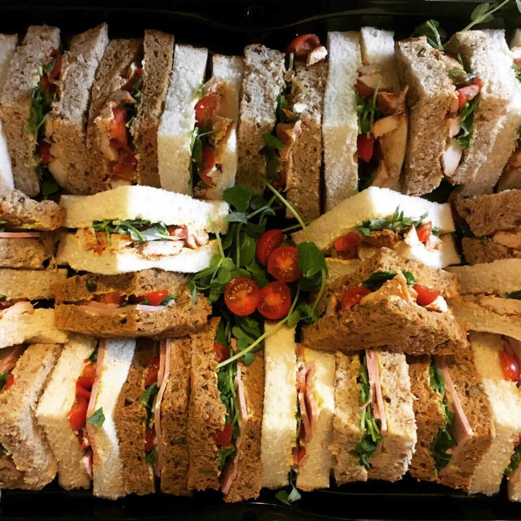 Circular platter of assorted finger sandwiches with vegetable fillings and herb garnish