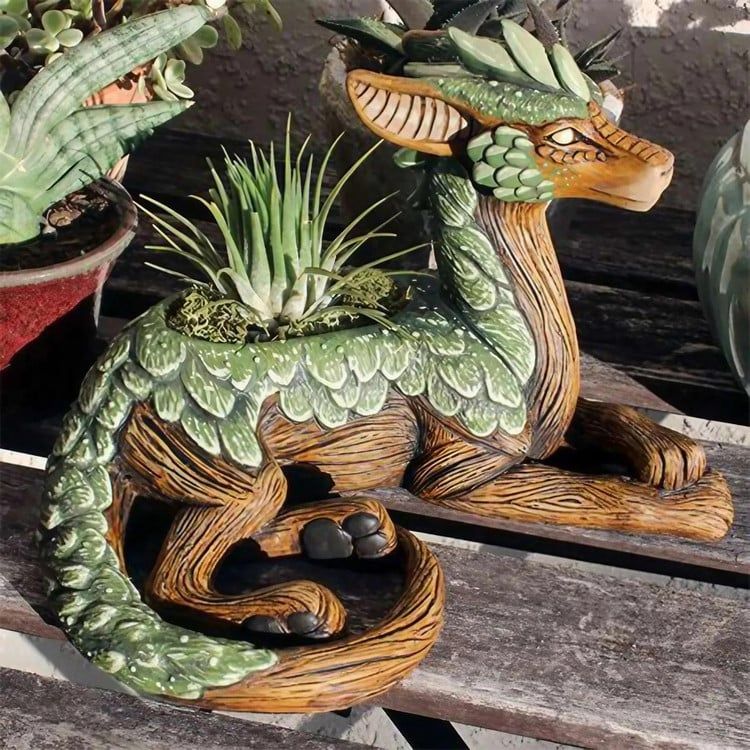 Green and brown dragon statue on a wooden bench next to potted plants