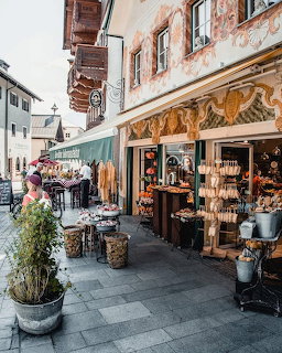 Quaint European street with outdoor cafe, shop front, and old buildings
