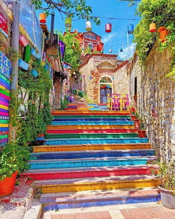 Rainbow-colored staircase in a bright Mediterranean alley with flowers and lanterns