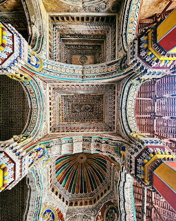 Looking up at ornate cathedral ceiling with painted vaults, arches, and detailed dome