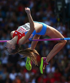 Female athlete clearing a high jump bar with arched back at a track and field event