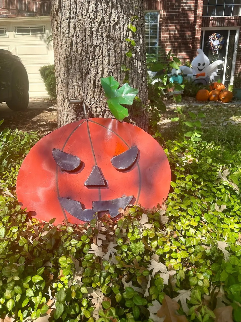 Large inflatable orange pumpkin decoration with jack-o'-lantern face in front yard