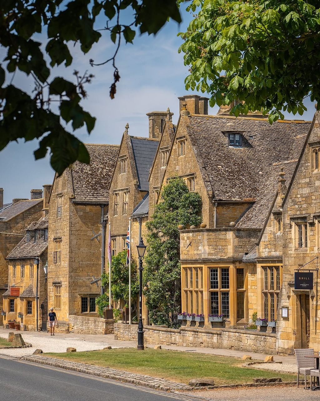 Cotswold stone cottage with thatched roof and flower garden in an English village