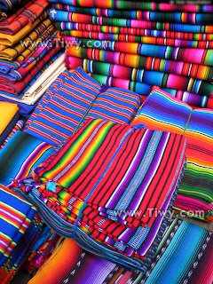 Stacked colorful striped woven textiles in rainbow patterns