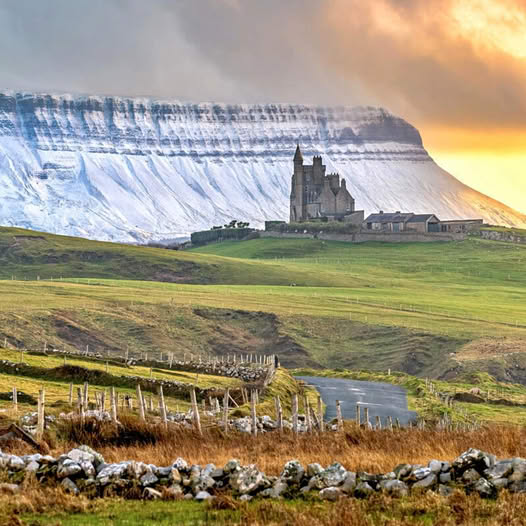Castle on green hill with striped mountain cliff and sunset sky