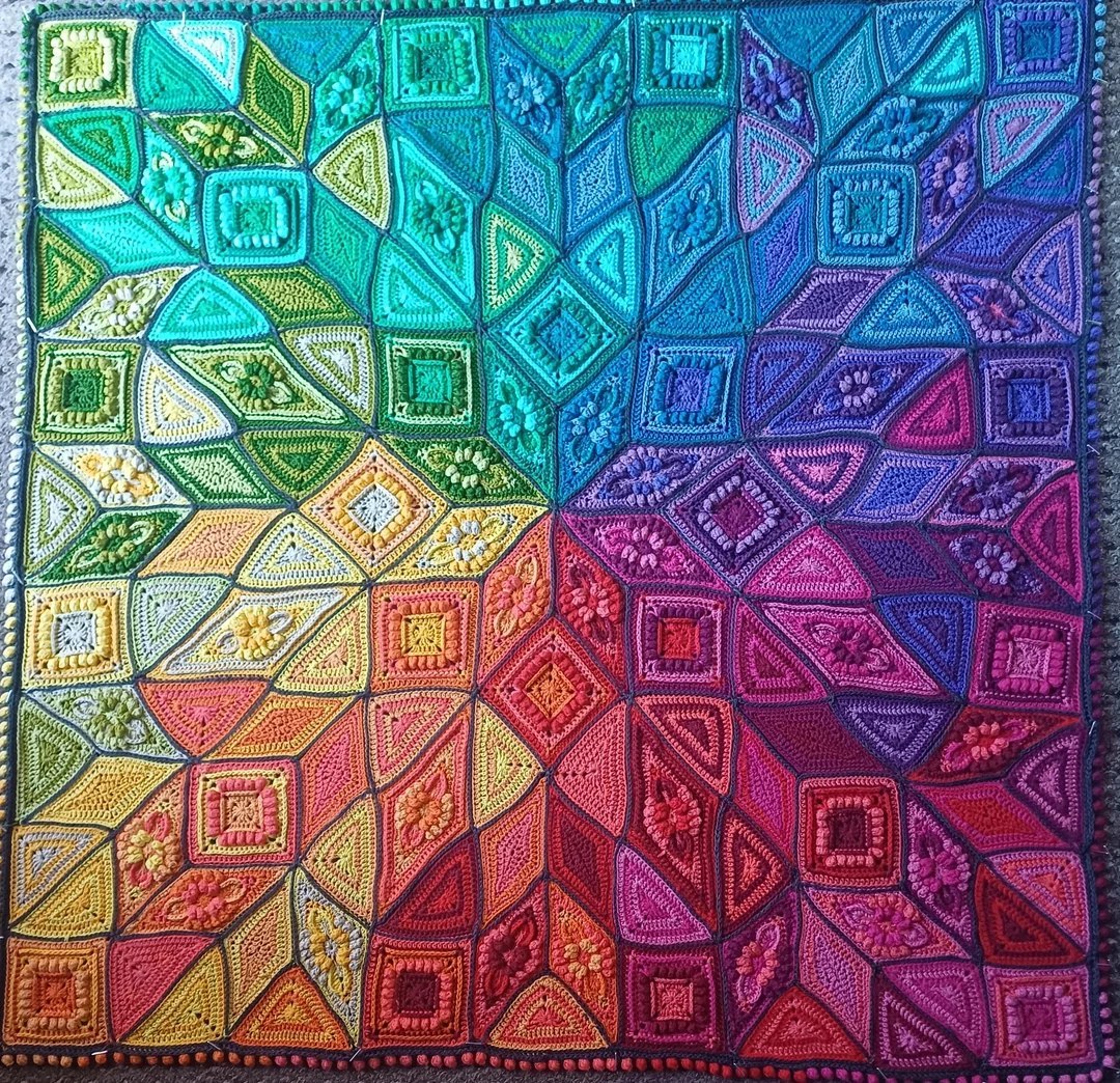 Colorful geometric quilt with rainbow gradient and symmetrical diamond pattern in detailed stitching