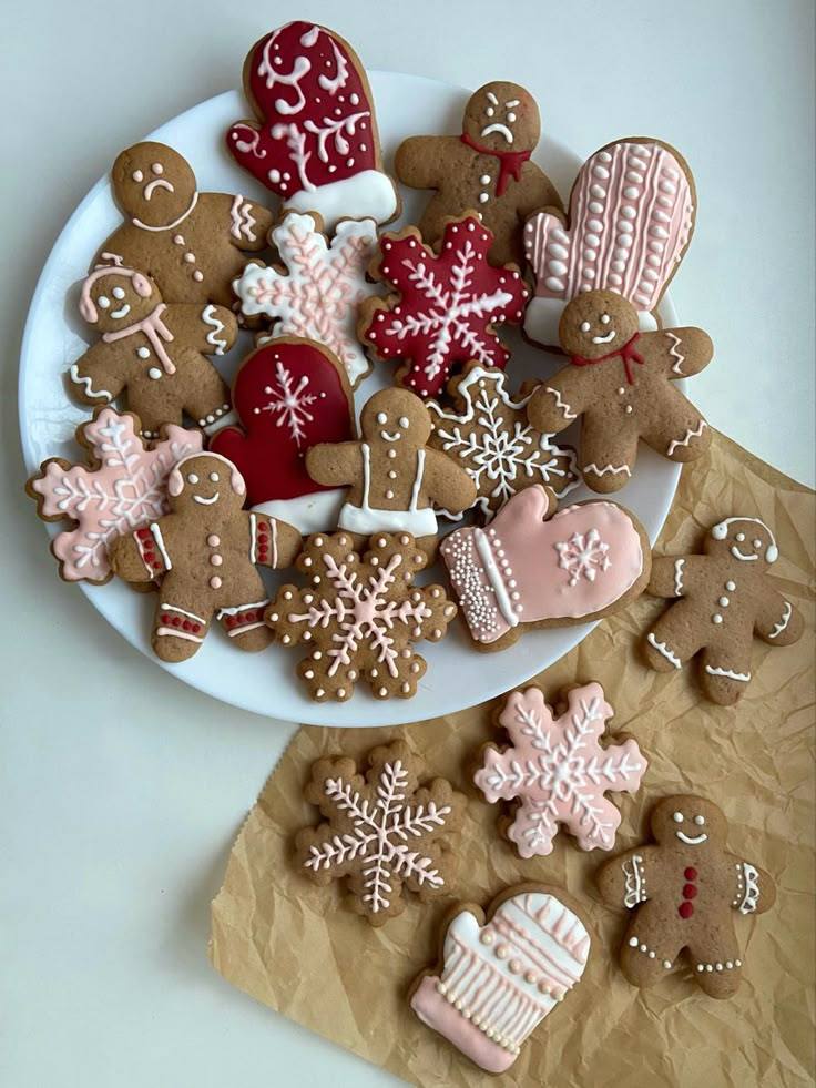 Decorated gingerbread cookies in Christmas shapes including gingerbread men, snowflakes, and mittens on white plate