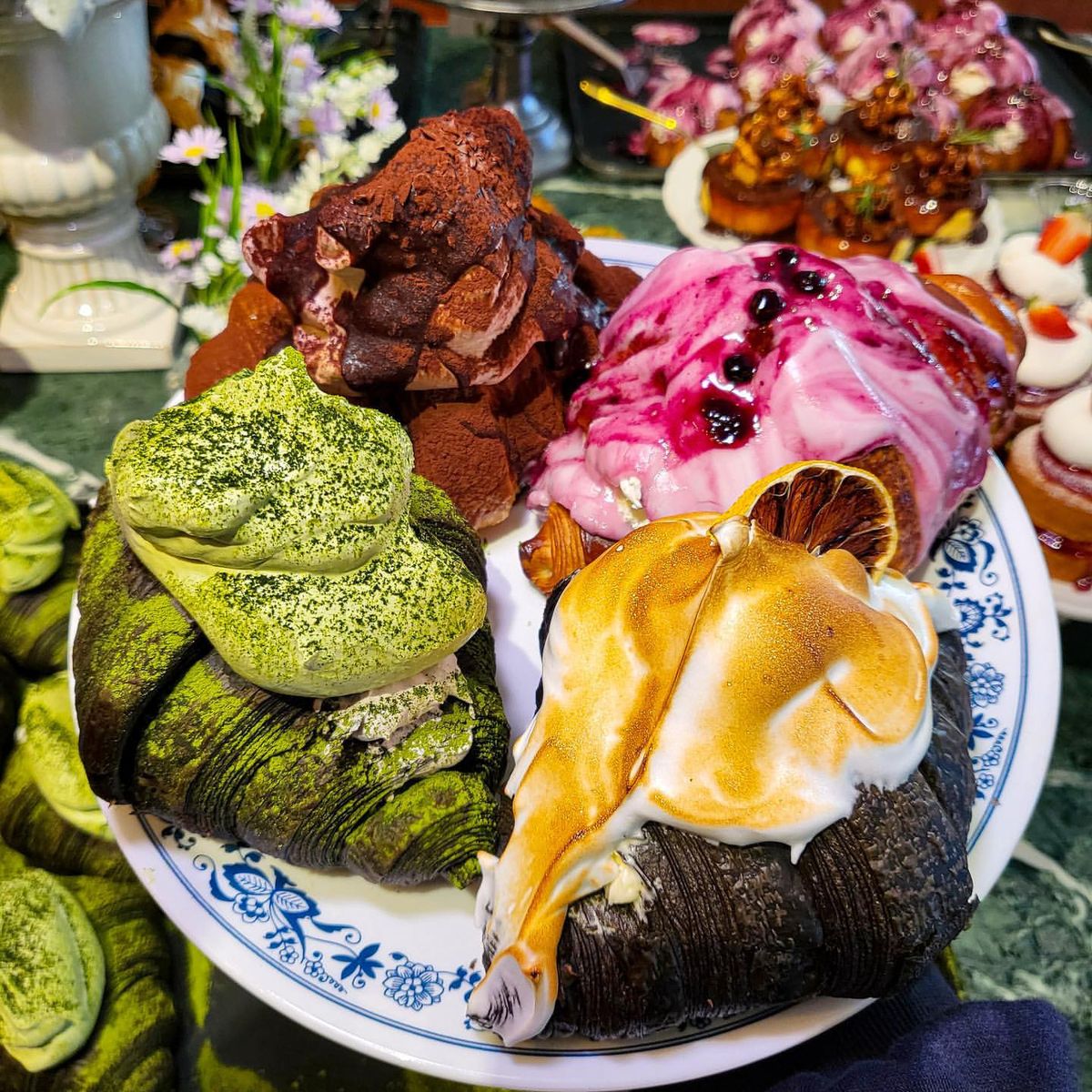 Plate of assorted colorful pastries with cream, fruit toppings, and chocolate croissants