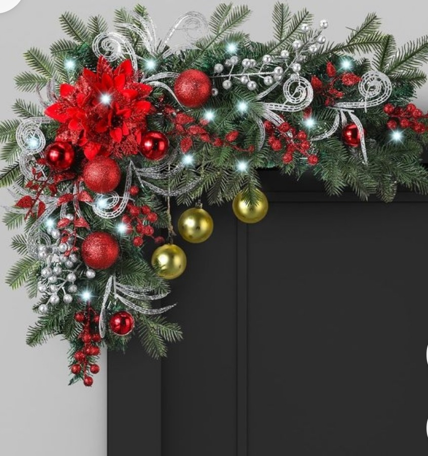 Christmas door swag with red poinsettias, ornaments, pine branches and silver ribbons on dark wood
