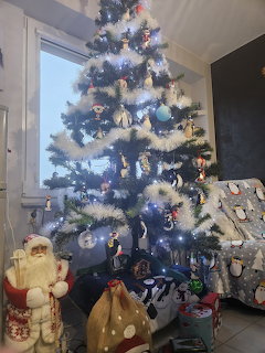Decorated Christmas tree with white lights and ornaments in a living room with presents underneath