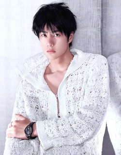 Portrait of a young man in a white textured sweater with dark hair and a wristwatch
