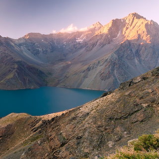 Rocky mountains above a deep blue alpine lagoon at El Morado, Chile