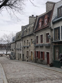 Historic stone buildings with mansard roofs along cobblestone street in Old Quebec City