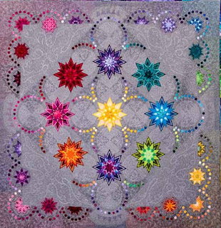 Colorful patchwork quilt with rainbow star pattern and decorative curved stitching on gray fabric