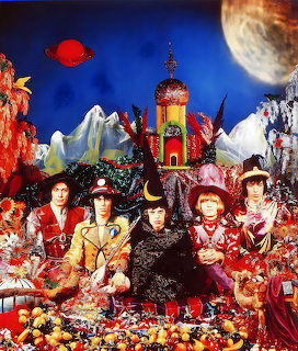 The Rolling Stones in elaborate psychedelic costumes seated among flowers and fruit with a fantasy backdrop
