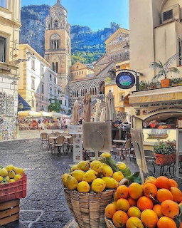 Sunny Amalfi town square with lemon market stalls, historic cathedral, and mountain cliffs