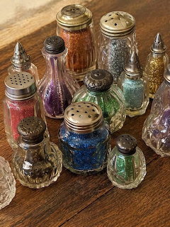 Colorful vintage glass glitter shakers arranged on a wooden table