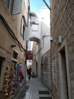 Narrow stone alley in Split Croatia old town with arch and pedestrians