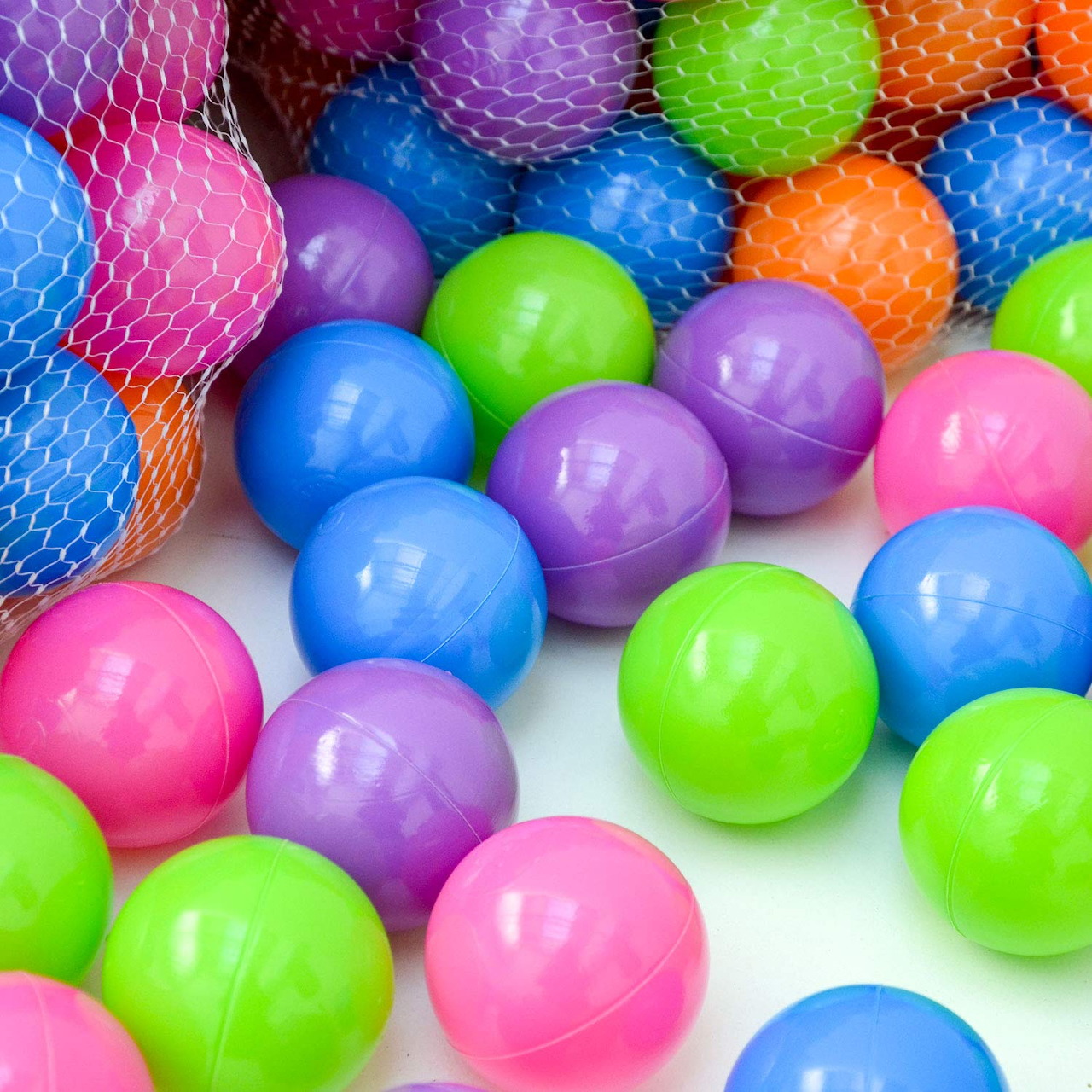 Colorful plastic balls in pink, blue, green, purple and orange scattered on white background