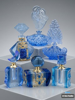 Ornate blue and clear glass perfume bottles and vanity containers arranged on a white surface
