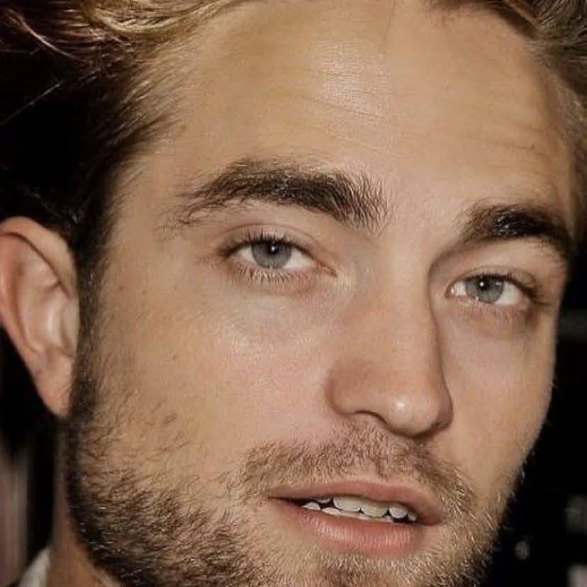 Close-up portrait of Robert Pattinson with light eyes and short beard