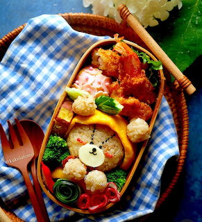 Kawaii-style bento box with bear-shaped rice, vegetables, and colorful food arranged decoratively in wooden container