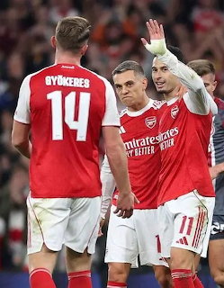 Arsenal FC football players in red jerseys celebrating together on the pitch