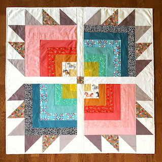 Colorful patchwork quilt with geometric log cabin blocks and triangle border