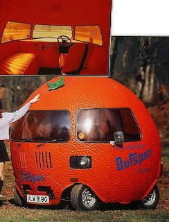 A round orange-shaped novelty car with Outspan branding and a wooden steering wheel detail inset.