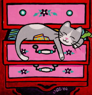 Gray cat sleeping contentedly on pink dresser drawers with flowers