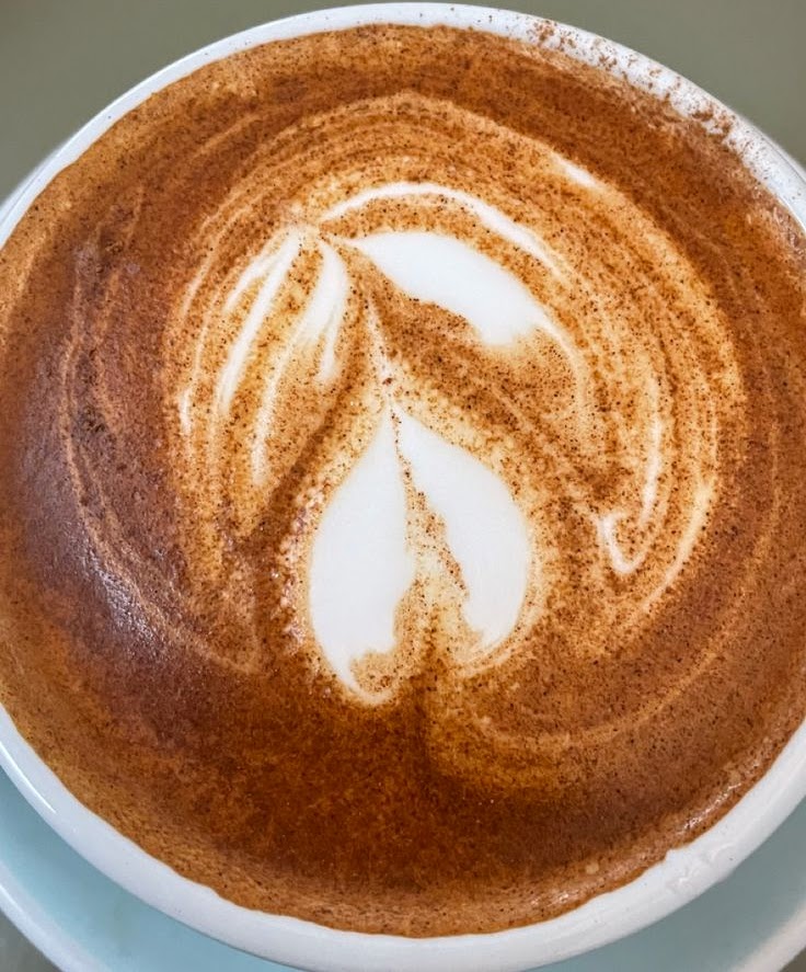 Overhead view of coffee latte with heart-shaped foam art in cup