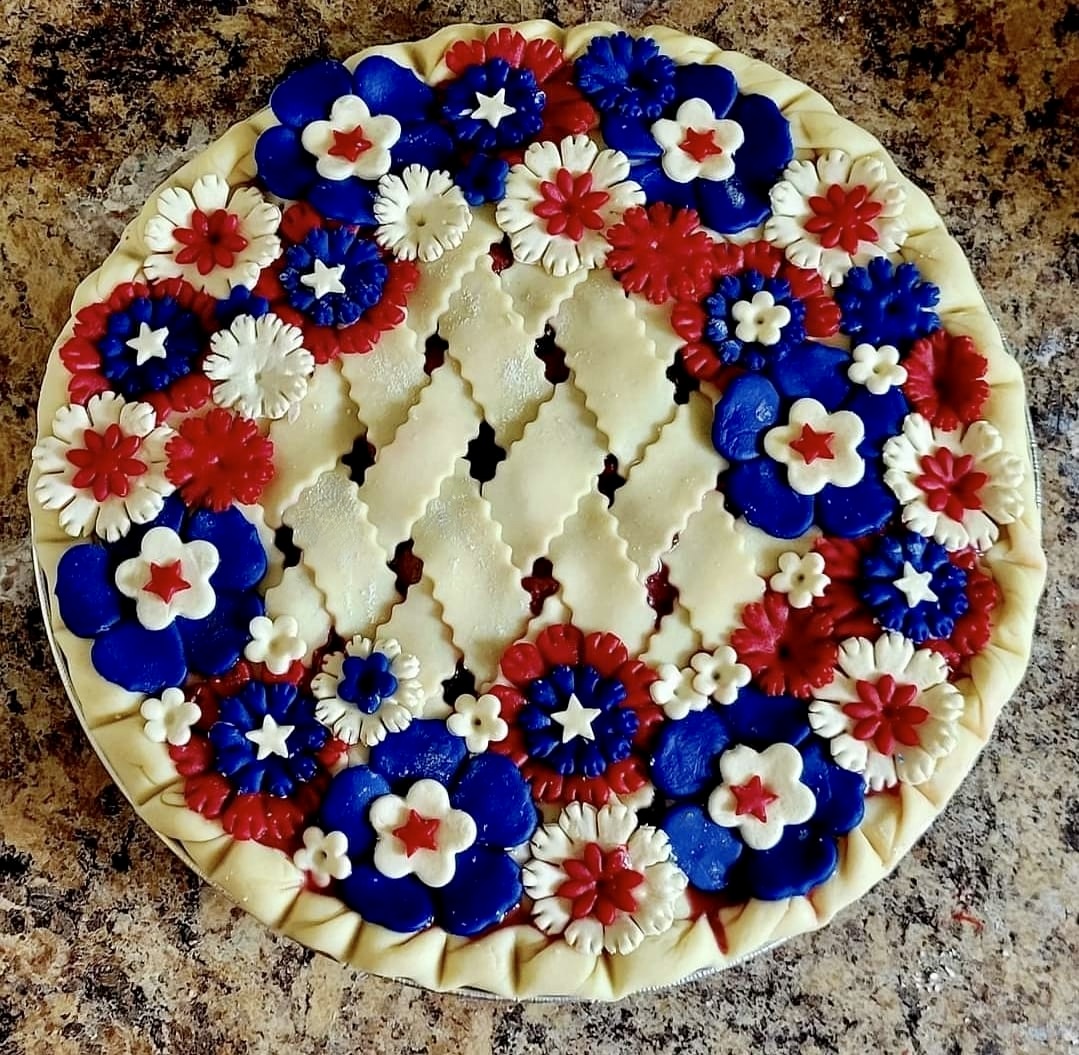 Decorated pie with red, white, and blue flower toppings on a countertop