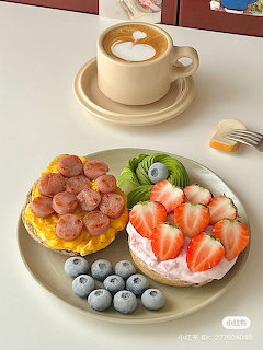 Open-faced bagel with cream cheese, grapes, strawberries, and blueberries on a plate with coffee
