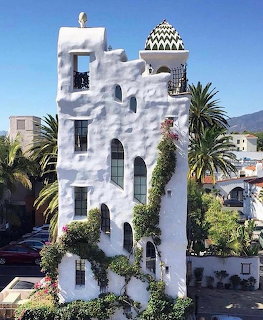 White multi-story Ablitt Tower with arched windows and zigzag-patterned cupola amid palm trees in Santa Barbara