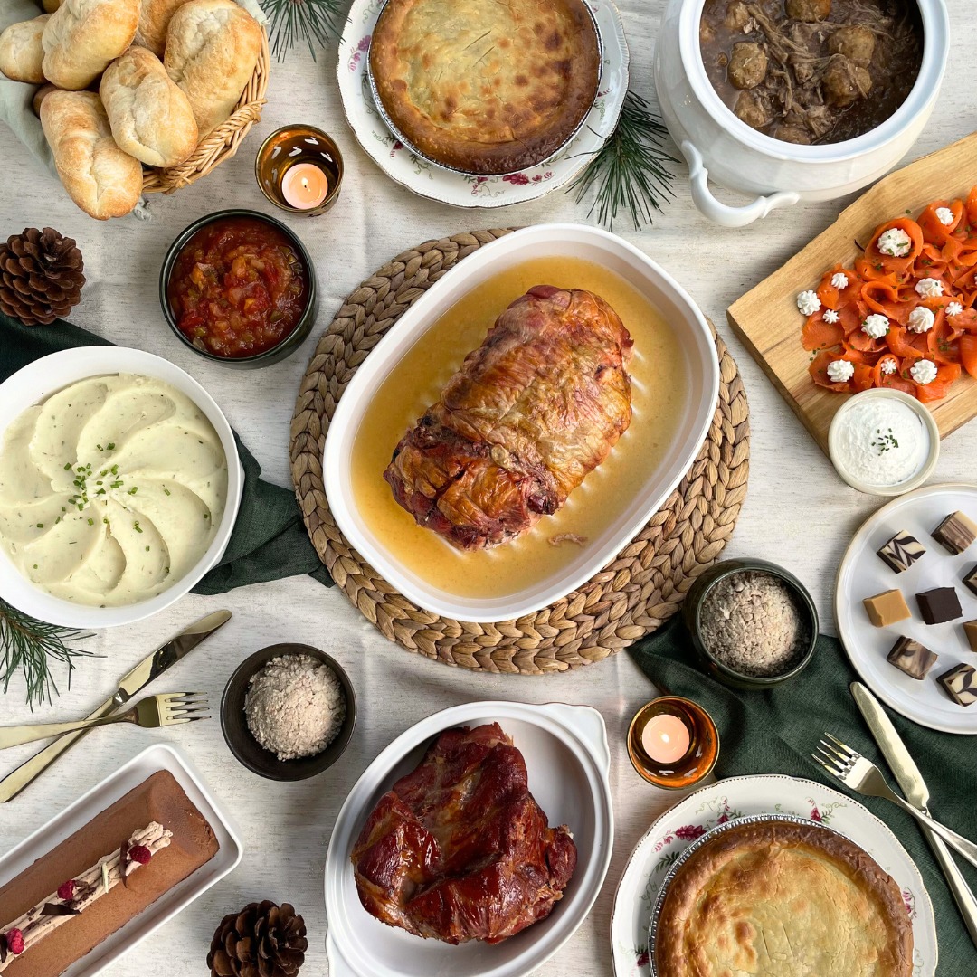 Overhead shot of festive holiday buffet spread with roasted turkey, pies, appetizers and candles on white table