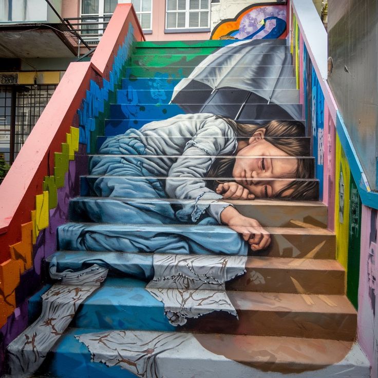 Street art mural of sleeping person painted across outdoor staircase with rainbow-colored railings