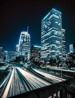 Illuminated city skyscrapers at night with highway light trails