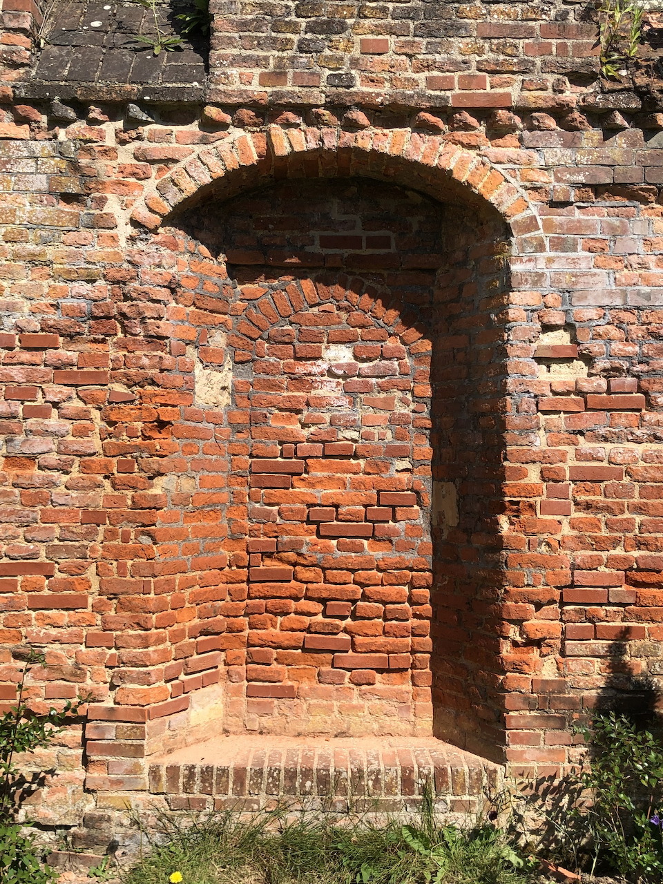 Old red brick wall with a recessed arched niche, historic garden architecture