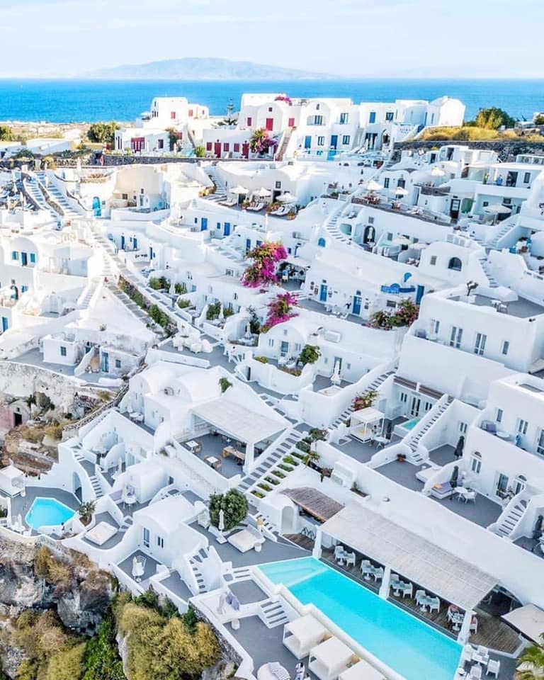 Whitewashed Santorini church with blue domes above the Aegean Sea