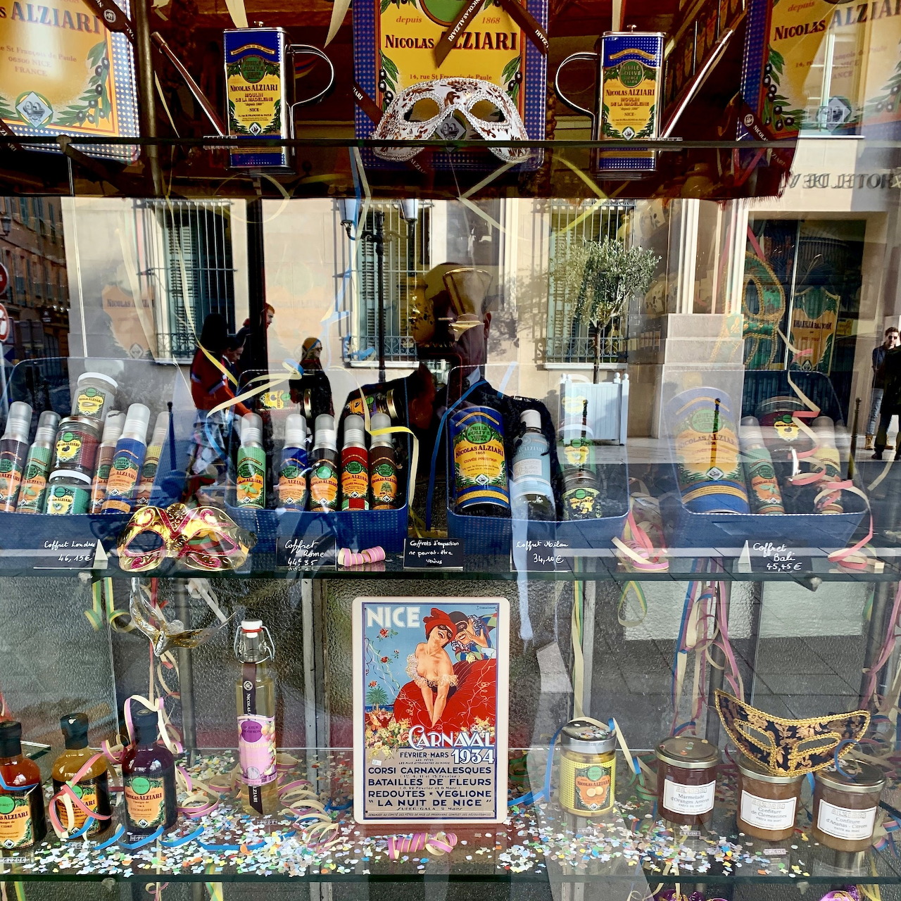 Shop window display in Nice France with olive oil bottles, vintage poster, and local products