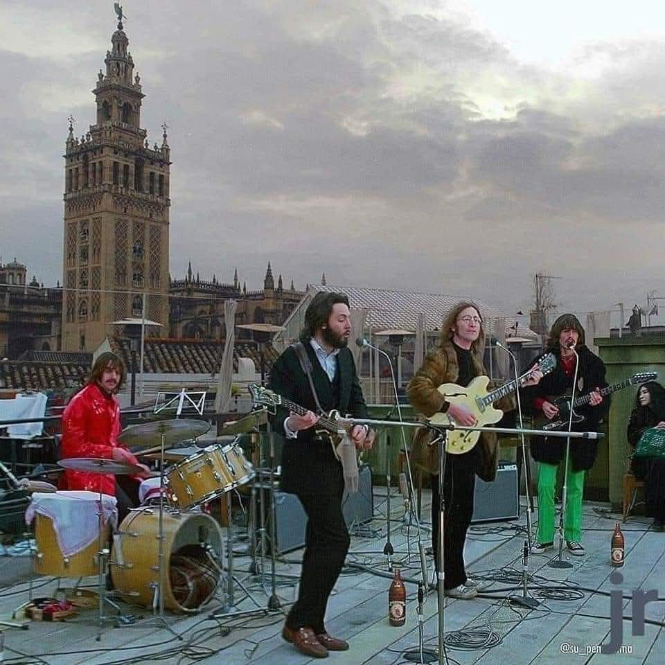 The Beatles performing on a rooftop with cathedral tower behind them
