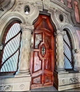Ornate wooden door framed by carved stone columns and arched windows