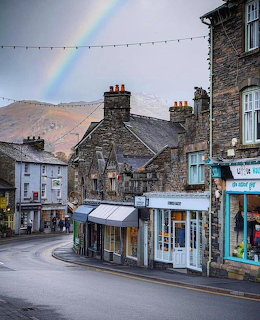Rainbow over a curved street with stone buildings in Ambleside, Lake District